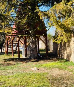 ein Baum mit Holzkonstruktion neben einem Zaun in der Unterkunft Holiday home Green Kiss in Vinkovci