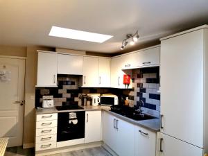 a kitchen with white cabinets and black appliances at Sunflower Apartment, Family accommodation Near Tenby in Pembrokeshire in Tenby