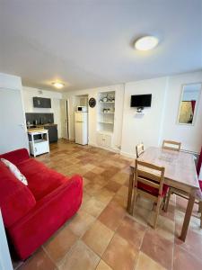 ein Wohnzimmer mit einem roten Sofa und einem Tisch in der Unterkunft Gîte de Ponpon, à proximité du Zoo et des Châteaux de la Loire in Selles-sur-Cher