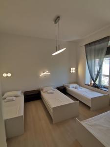 een witte kamer met 2 bedden en een raam bij Hostel Jadran in Pag