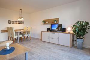 uma sala de estar com uma mesa de jantar e uma televisão em Feriendorf Papillon Wohnung 10-3 em Boltenhagen