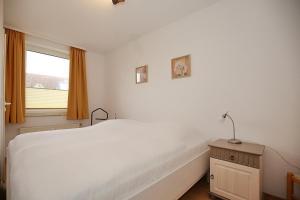 a bedroom with a white bed and a window at Sünnslag Wohnung 057 in Boltenhagen