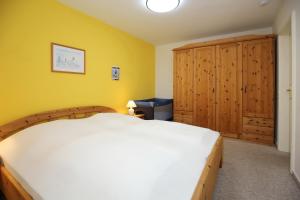een slaapkamer met een wit bed en een gele muur bij Nordstern Wohnung 12 in Boltenhagen