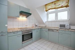 cocina con armarios azules, fregadero y ventana en Sünnslag Wohnung 148, en Boltenhagen