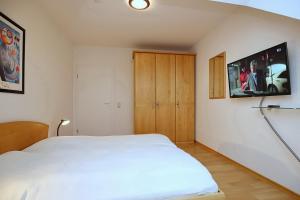 a bedroom with a white bed and a tv on the wall at Sünnslag Wohnung 148 in Boltenhagen
