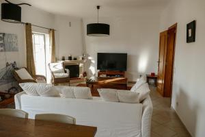uma sala de estar com um sofá branco e uma televisão em Encosta das Oliveiras 49D em Vilamoura