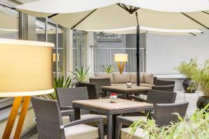 a patio with tables and chairs and umbrellas at IntercityHotel Wien in Vienna