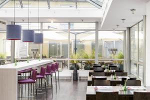 a restaurant with purple chairs and tables and windows at IntercityHotel Wien in Vienna
