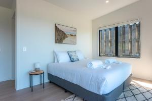 a bedroom with a large white bed with a window at Luna Cottage. Stunning ocean views on Waiheke in Oneroa