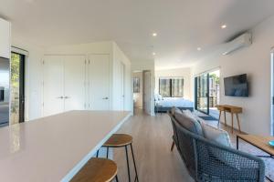 a kitchen and living room with a large counter and chairs at Luna Cottage. Stunning ocean views on Waiheke in Oneroa
