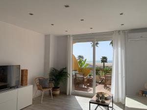 a living room with a flat screen tv and a patio at BEACH FRONT ATICO WIFI in Tarifa