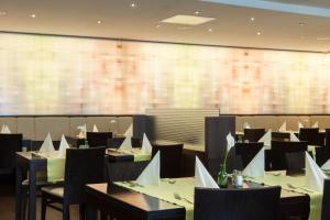 a dining room with tables and chairs and a large screen at IntercityHotel Wien in Vienna