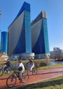 un gruppo di persone che vanno in bicicletta di fronte a edifici alti di Twins tower orbi city a Batumi