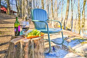 a blue chair sitting on a tree stump with a glass of wine at Serene Cabin with Riverfront Views and Access! in Fayetteville