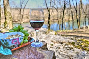 a glass of wine sitting on a table with a bowl of grapes at Serene Cabin with Riverfront Views and Access! in Fayetteville