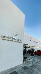 a white building with a car parked in a parking lot at Hotel Mencia Subbética in Doña Mencía