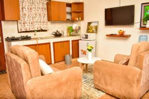 a living room with three chairs and a kitchen at Unique, Compact Studio Apartment in Kisumu