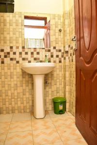 a bathroom with a sink and a green trash can at Unique, Compact Studio Apartment in Kisumu