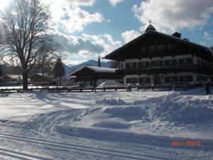 a snow covered yard with a large building in the background at Familien-Bauernhof-Berghammer in Rottach-Egern