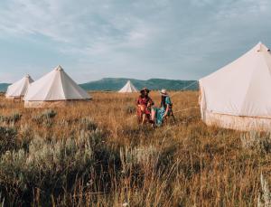 um grupo de pessoas num campo com tendas em Wander Camp Yellowstone em Island Park