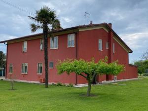 un edificio rosso con una palma di fronte di Cygnus Bed & Breakfast a Lido di Jesolo