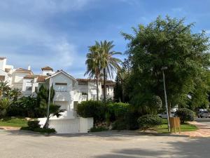 una casa blanca con palmeras frente a una calle en Apartamento en Playa del Infante (Costa Ballena), en Rota