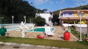 a swimming pool with a statue of swans next to a house at Pousada 7 Estrelas in Ipiabas