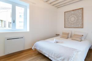 a white bedroom with a bed and a window at Ambiance bohème in Roanne