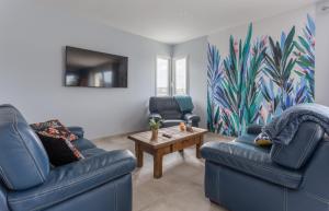 a living room with two blue chairs and a table at La proue - appt avec terrasse à moins de 100m de la plage in Saint-Côme-de-Fresné