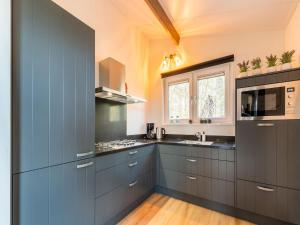 a kitchen with blue cabinets and a sink and a microwave at Cosy holiday home in the countryside in Hellendoorn
