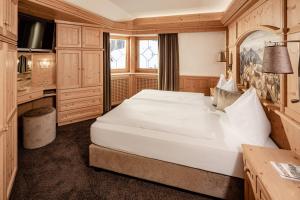 a bedroom with a large white bed in a room at Suites Hotel Garden in Selva di Val Gardena