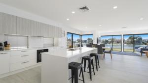 a kitchen with white cabinets and a table with stools at FLOATING ON THE CANALS - 80 COMMODORE CRES in Port Macquarie