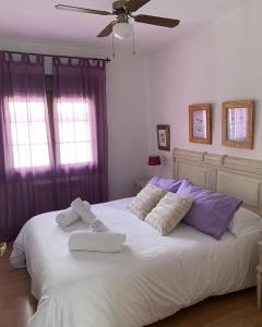 a bedroom with a large white bed with towels on it at El balcón de Araceli in Cercedilla
