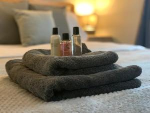 a towel sitting on a bed with two bottles of soap at Modern Cosy Warm Home With Free Parking in Chelmsford