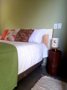 um quarto com uma cama com lençóis brancos e um candeeiro em Suítes Manjuba Praia de Sta Tereza em Ilhabela