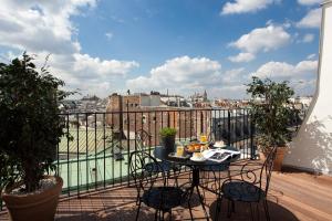 a table on a balcony with a view of a city at H&ocirc;tel des 3 Poussins in Paris