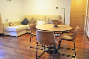 sala de estar con mesa, sillas y sofá en Apartament acollidor amb una gran llar de foc by RURAL D'ÀNEU, en Esterri d'Àneu
