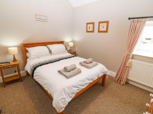 a bedroom with a bed with two towels on it at Coetsiws in Clynnog-fawr