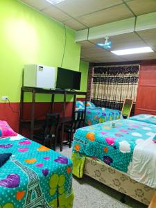 Habitación con 2 camas y escritorio con TV. en Hotel Kasa Kamelot Las Rosas, en Quetzaltenango