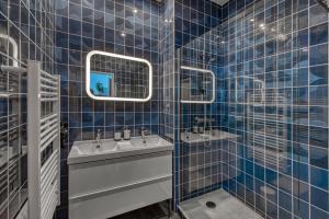 Ein blau gefliestes Badezimmer mit zwei Waschbecken und einem Spiegel in der Unterkunft Five to Sete - Gare - Centre-ville in Sète