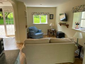 ein Wohnzimmer mit einer Couch und einem Sessel in der Unterkunft Oke Apple Cottage in Shillingstone