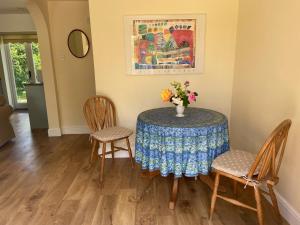 ein Esstisch mit einer Vase mit Blumen darauf in der Unterkunft Oke Apple Cottage in Shillingstone