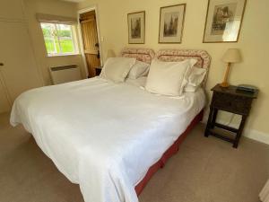 a bedroom with a large bed with white sheets and pillows at Oke Apple Cottage in Shillingstone