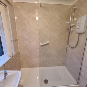 a shower with a glass door next to a sink at PREMIER - Whifflet Apartment in Coatbridge