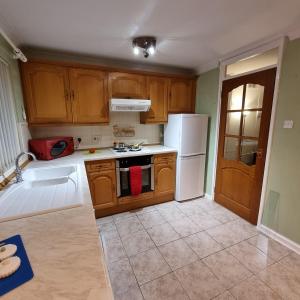 a kitchen with wooden cabinets and a white refrigerator at PREMIER - Whifflet Apartment in Coatbridge +18 photos