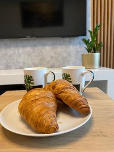 een bord met twee croissants op een tafel met twee kopjes bij Plac Unii Gdynia in Gdynia