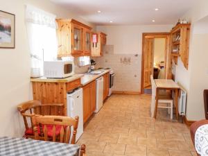 a kitchen with wooden cabinets and a white microwave at At the Crossroads in Louisburgh