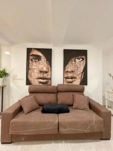 un sofá en una habitación con 2 caras en la pared en A Das Marías ESTUDIO, en Ourense