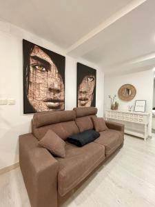 a brown couch in a living room with two pictures at A Das Marías ESTUDIO in Ourense