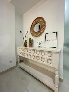 una consola blanca con un espejo en la pared en A Das Marías ESTUDIO, en Ourense